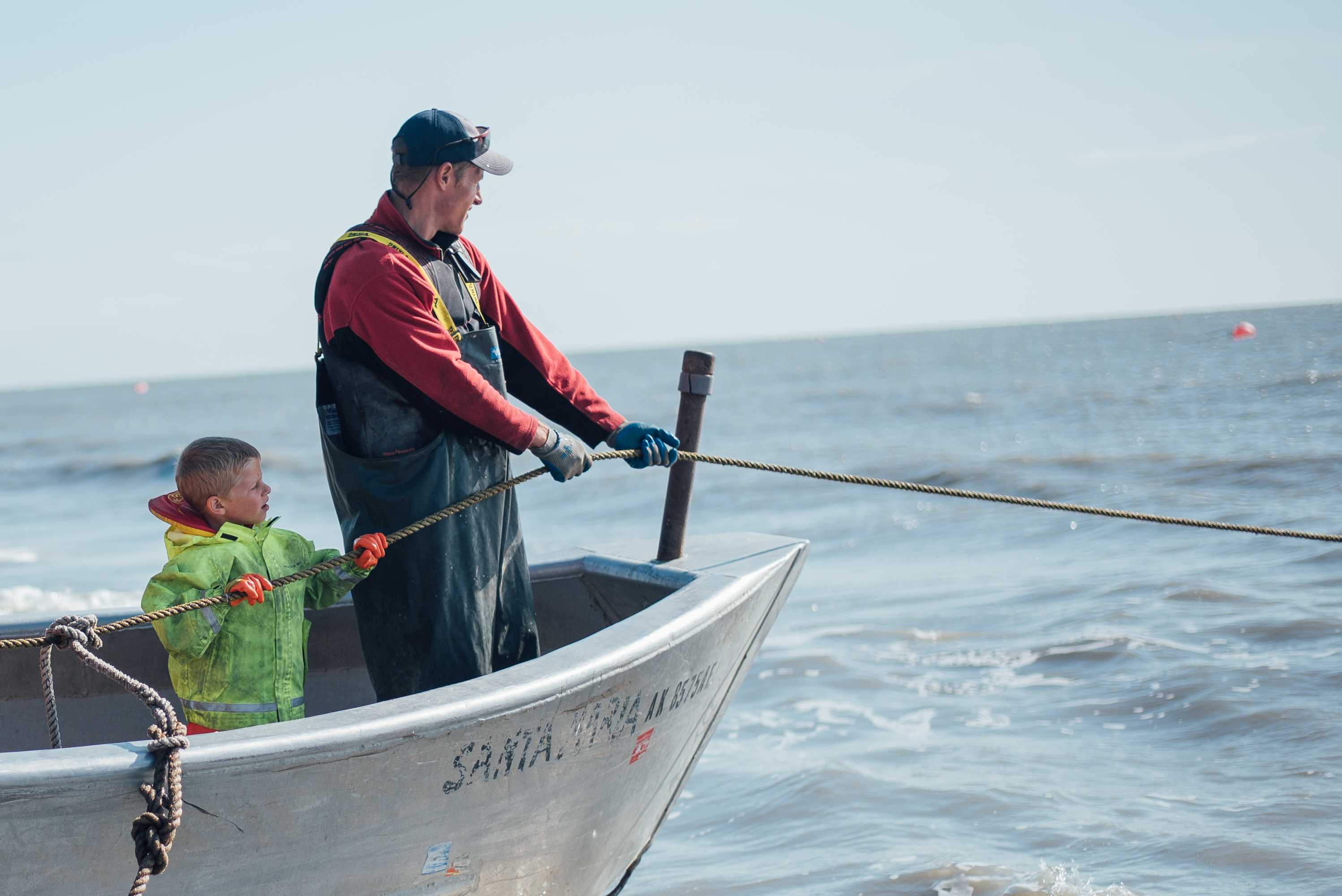A boy and his father prepare to check the nets.