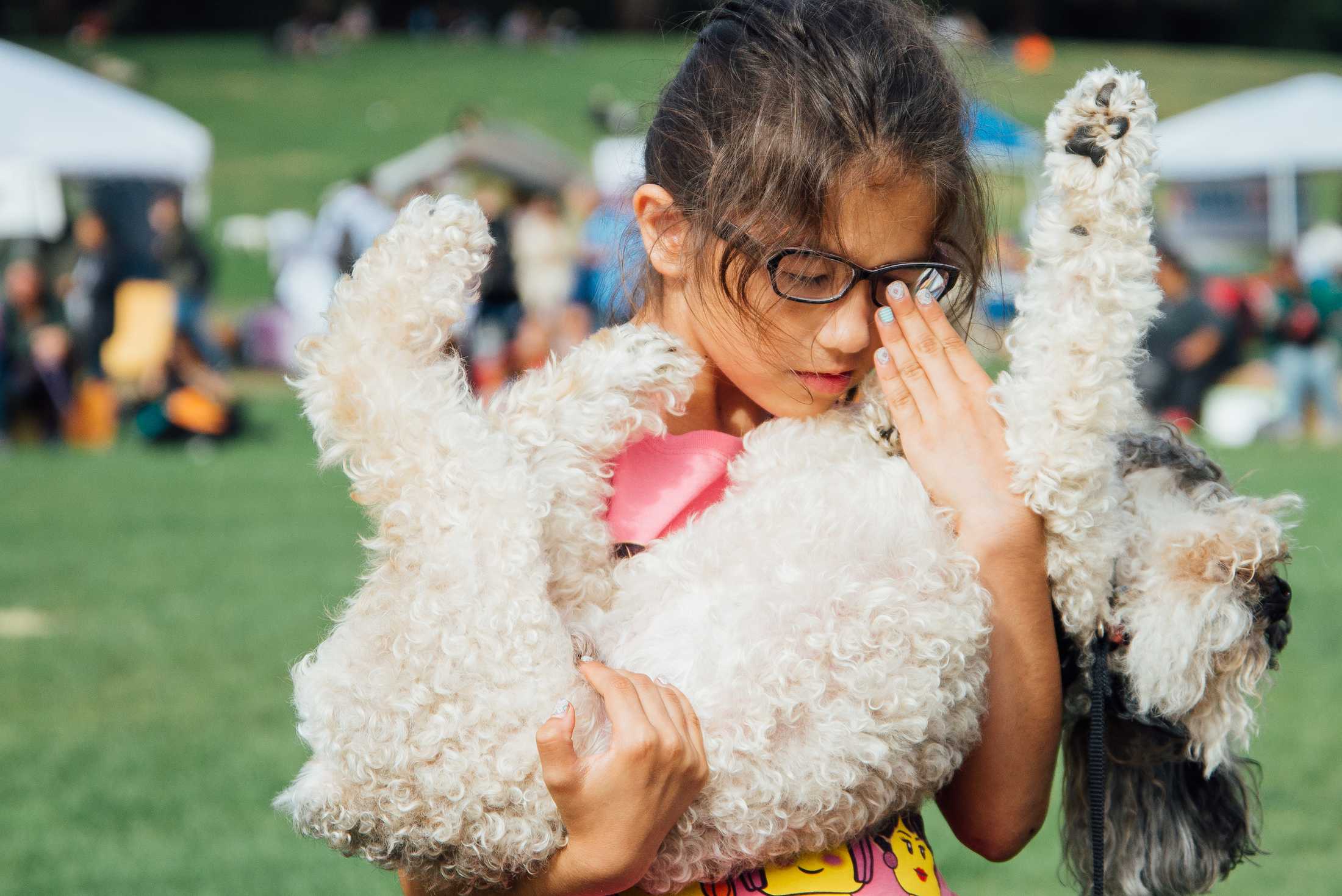 A young girl holds her dog at a Halloween pet costume festival.