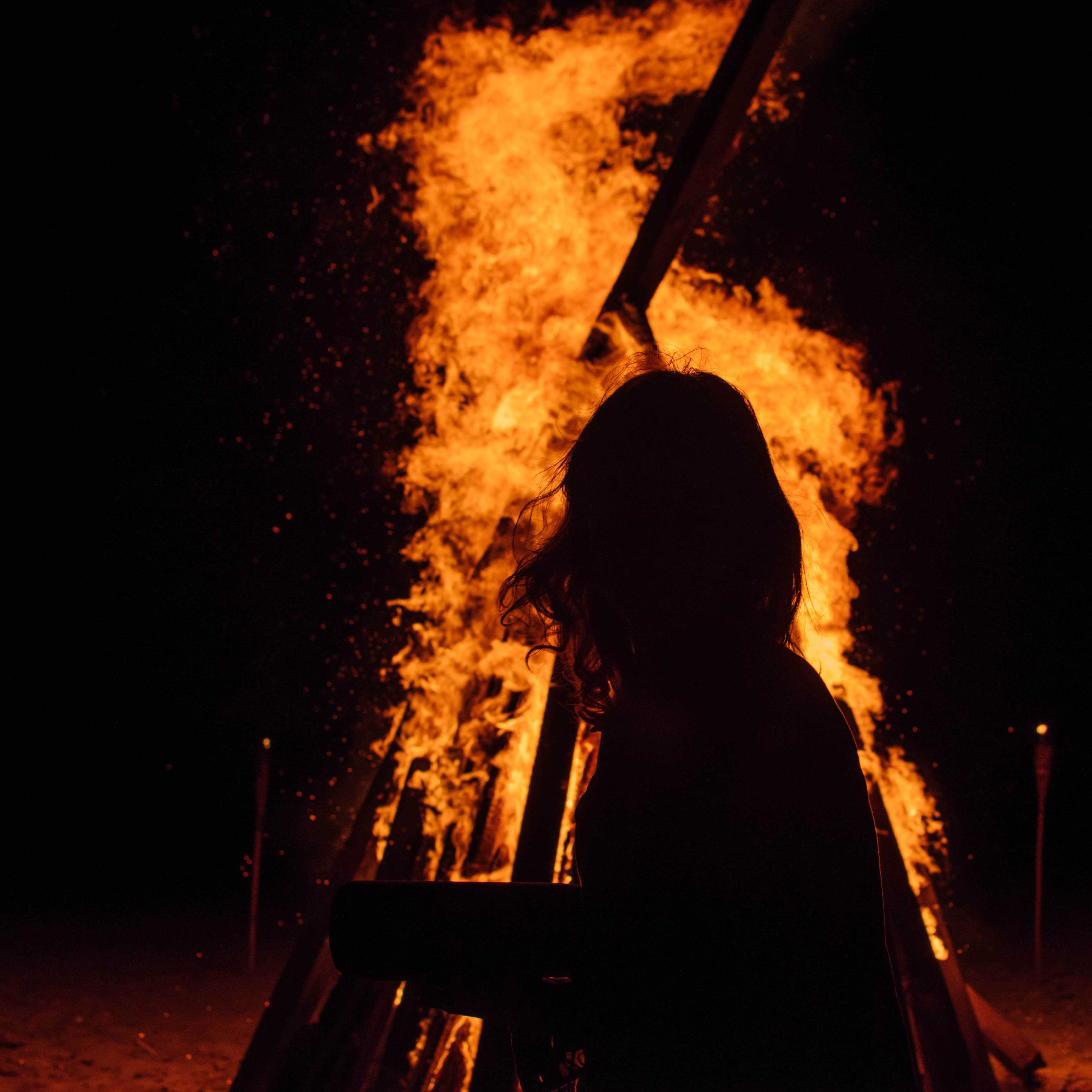 A kohai stands in front of a bonfire on the last night of camp.